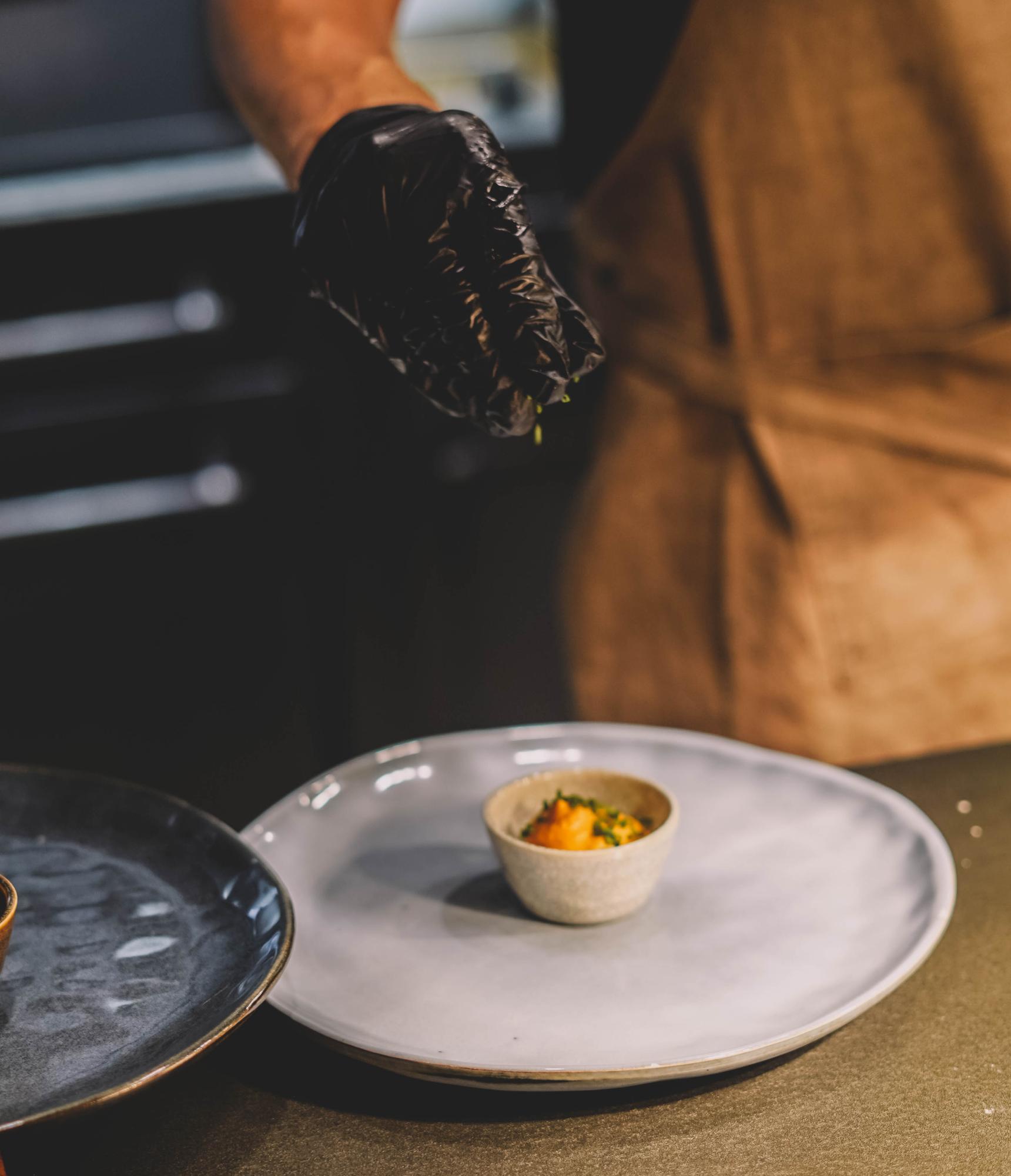 chef plating a composed dish on ceramic plate
